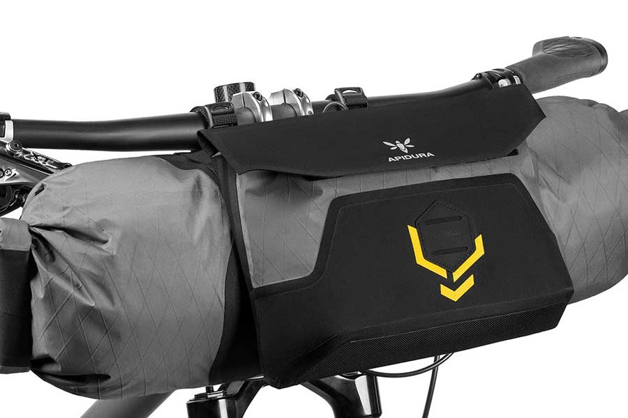 Apidura Backcountry Zubehörtasche wird an eine Lenkertasche geklipst