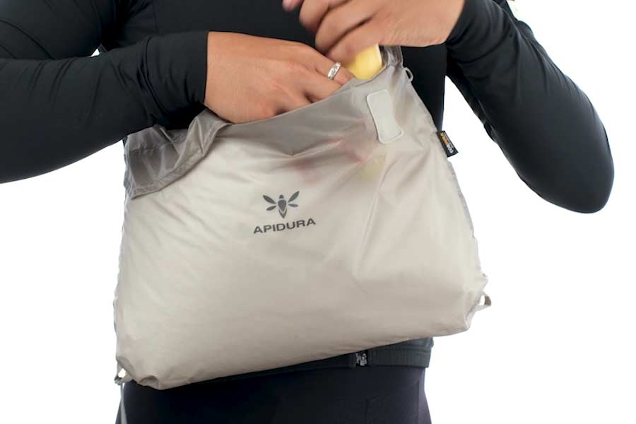 Hånd, der åbner velcrolukningen på Apidura Packable Musette