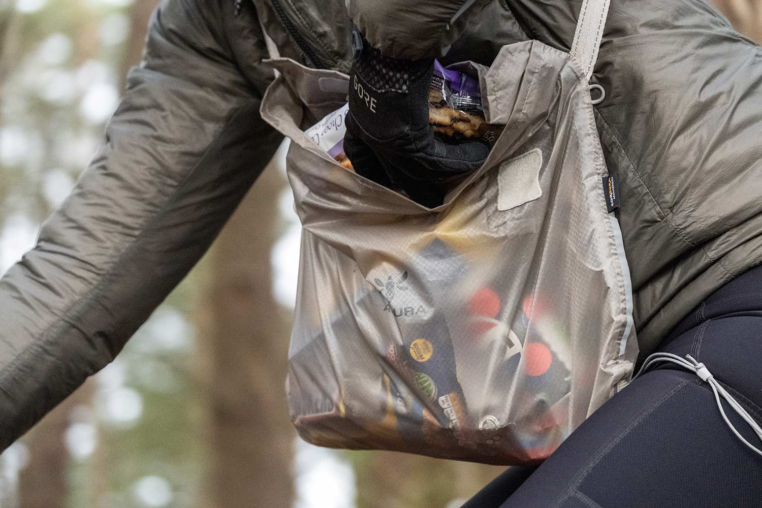 Cyklist, der rækker ned i en fuld Apidura Packable Musette på en tur i skoven