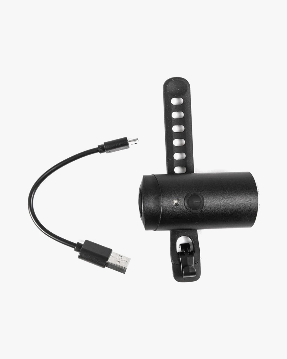 Glow front light lying beside a short USB charging cable, with the silicone strap opened out to show a row of holes