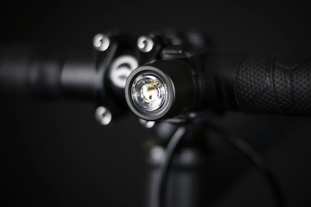 Reflection Mini front light on a bike handlebar beside the stem at night, its white lens in sharp focus against a dark background