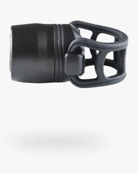 Reflection Mini front light seen from the side, a short black cylinder with the open silicone cage strap at the right