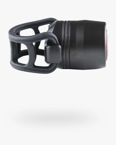 Reflection Mini rear light seen from the side, with the open silicone cage strap at the left and the red lens at the right end