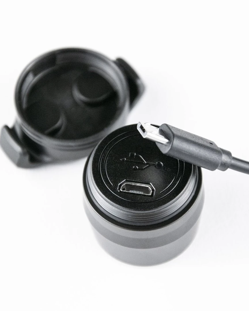 Close-up of the end of the Reflection Mini rear light with the USB symbol and a micro-USB port, a micro-USB plug above it and a black holder piece beside it