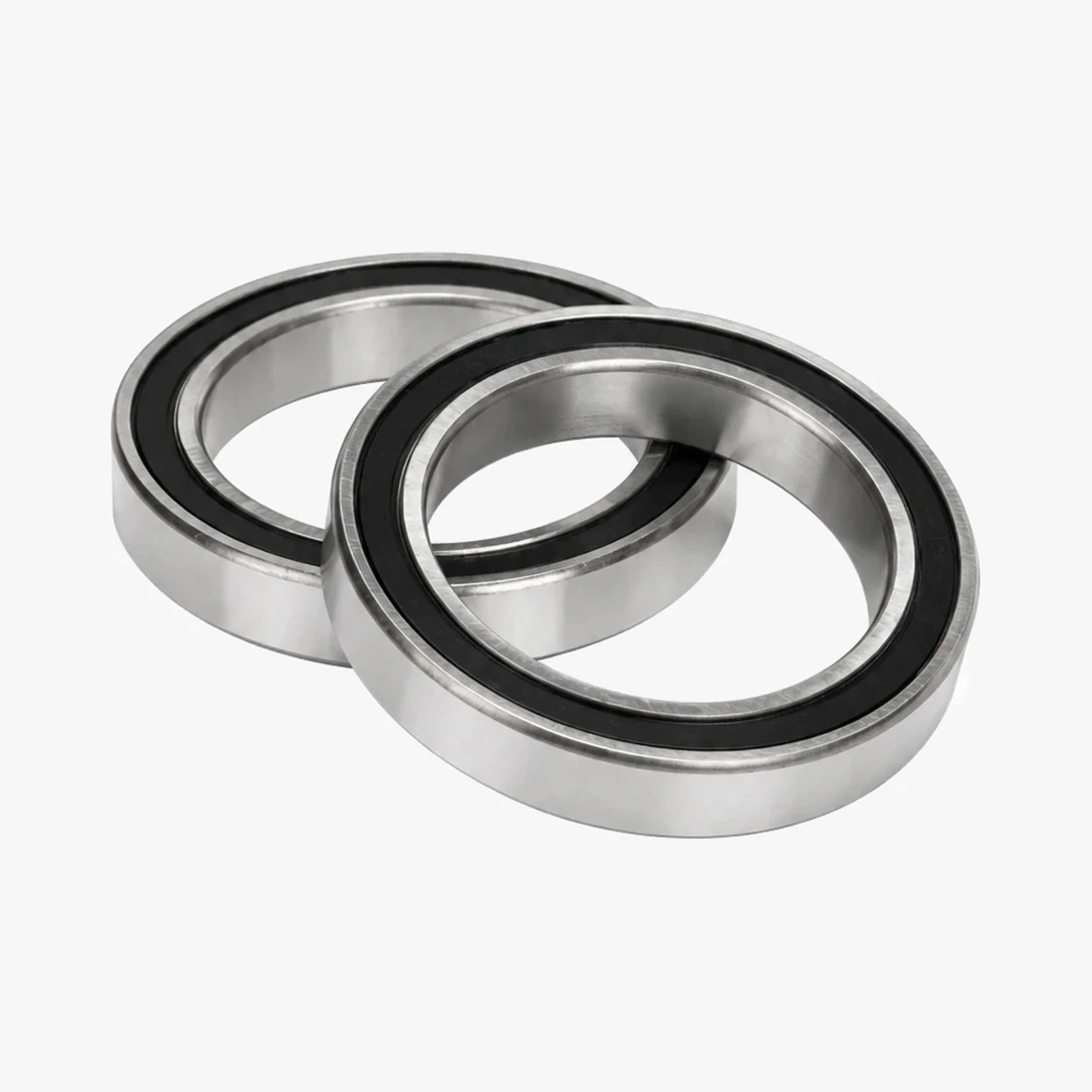 Two sealed 30 mm eccentric bottom bracket bearings with black seals and silver rings, one leaning on the other, on a light grey background