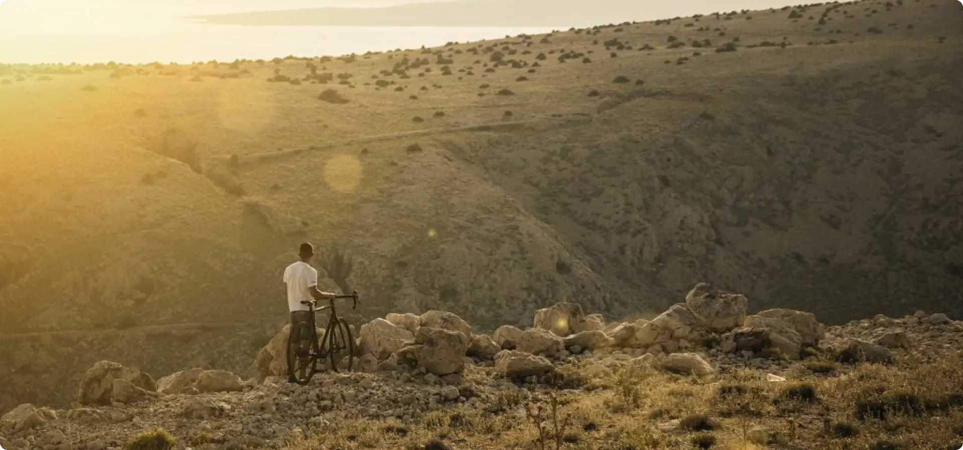 Rider standing next to a Booda Bike Hiker gravel bike on a sunlit hillside