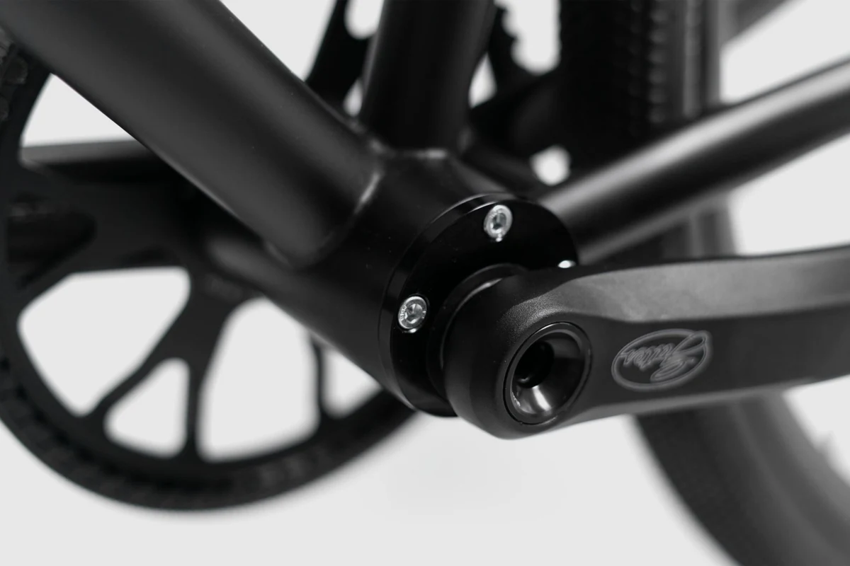 Eccentric bottom bracket cap with bolts and the crank axle of a Booda Bike Atlas, with the Gates sprocket behind