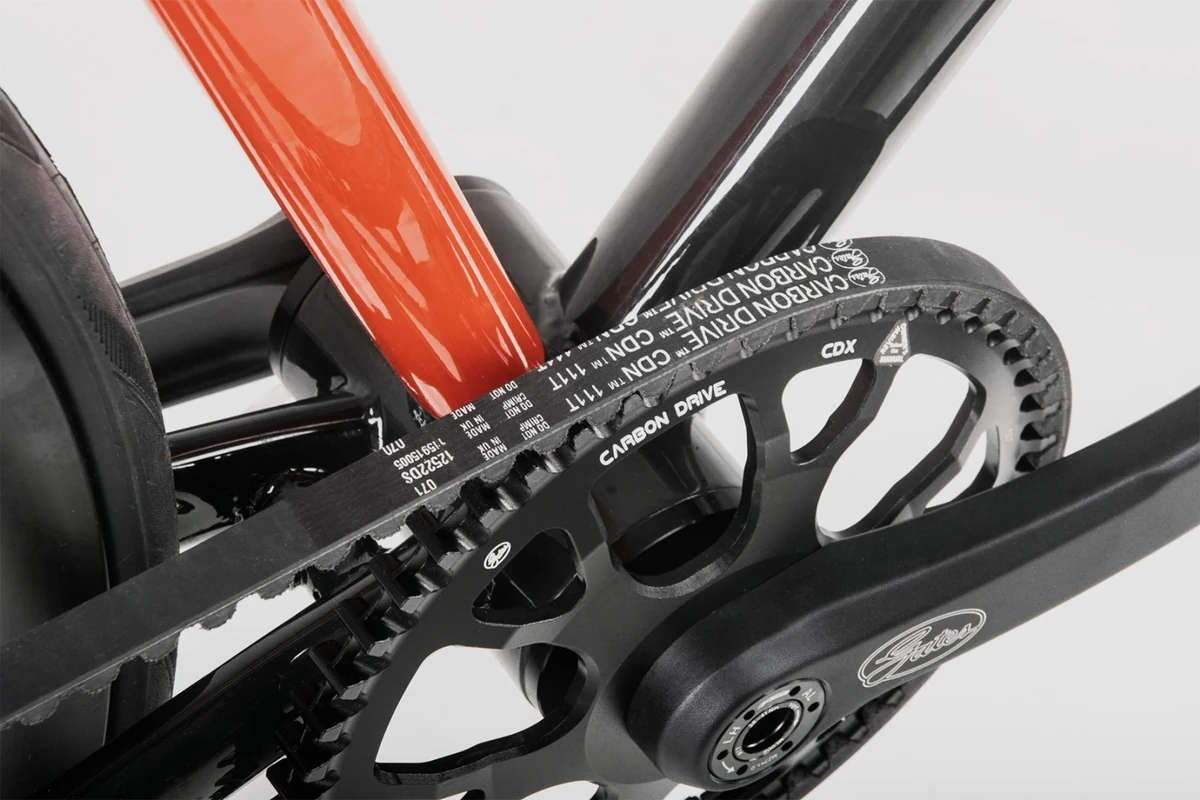 Gates carbon belt on the front sprocket beside an orange seat tube on a Booda Bike