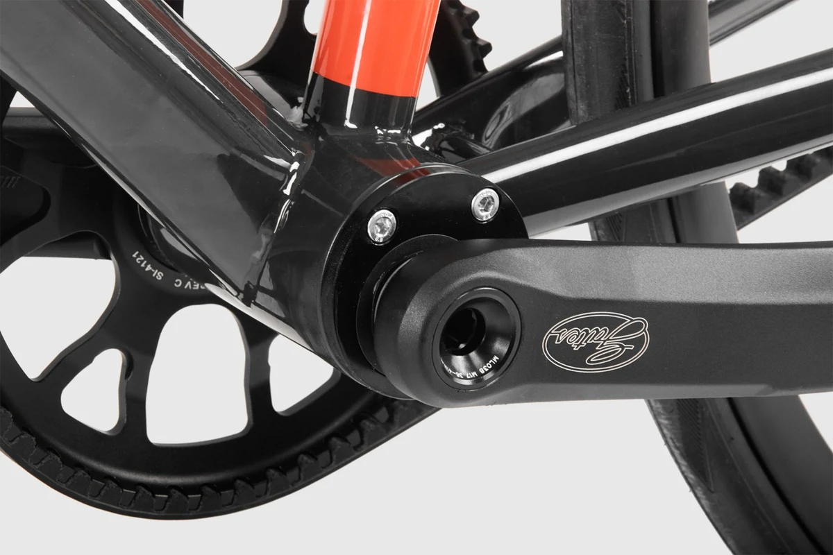 Bottom bracket shell and crank of a Booda Bike with an orange seat tube and the Gates sprocket