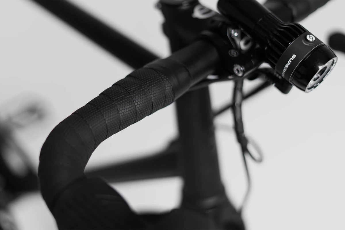 Black textured Multibender tape on the bend of a drop handlebar with a front light mounted next to the stem, on a Booda Bike Alpine