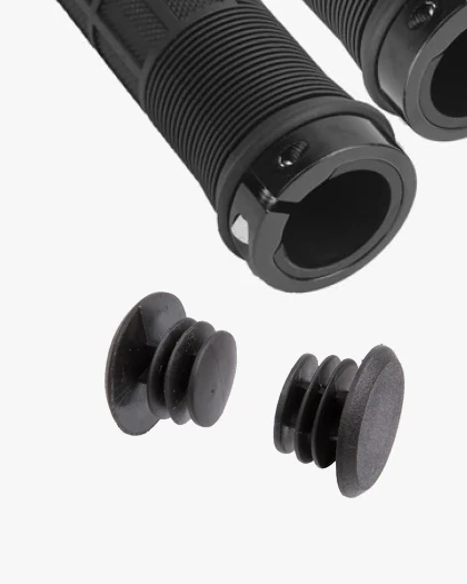 Close-up of the open end of a black Non Ergo grip with a black ring and a small screw, beside two black bar end plugs
