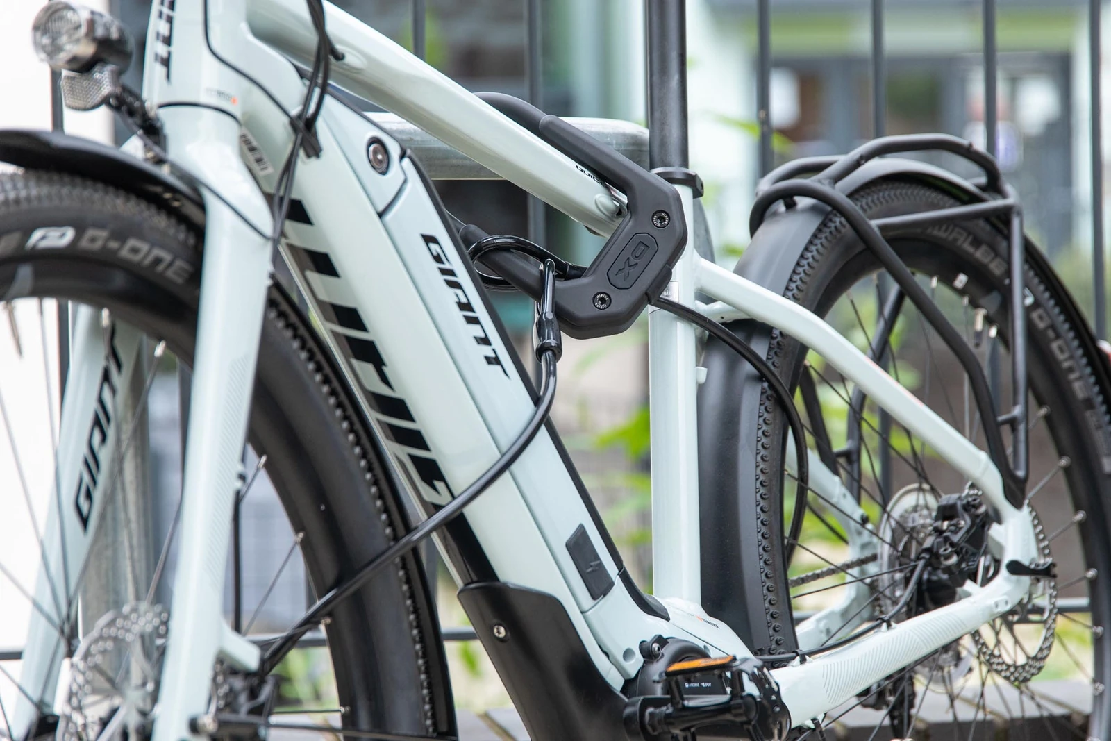 Hiplok DX D lock and cable securing a white Giant e-bike to a railing