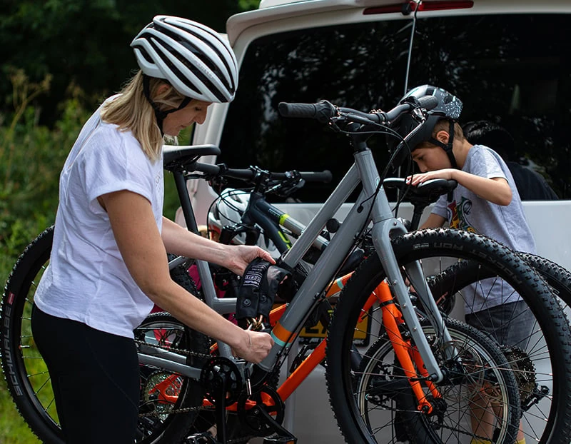 Woman and child locking bikes to a van bike rack with the Hiplok HOME GOLD chain