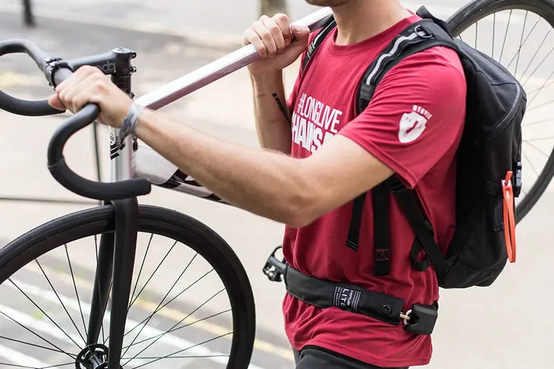 Rider wearing a Hiplok LITE chain lock round the waist while carrying a bike