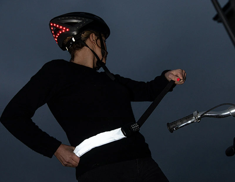 Woman fastening the Hiplok SPIN wearable chain lock round her waist at night
