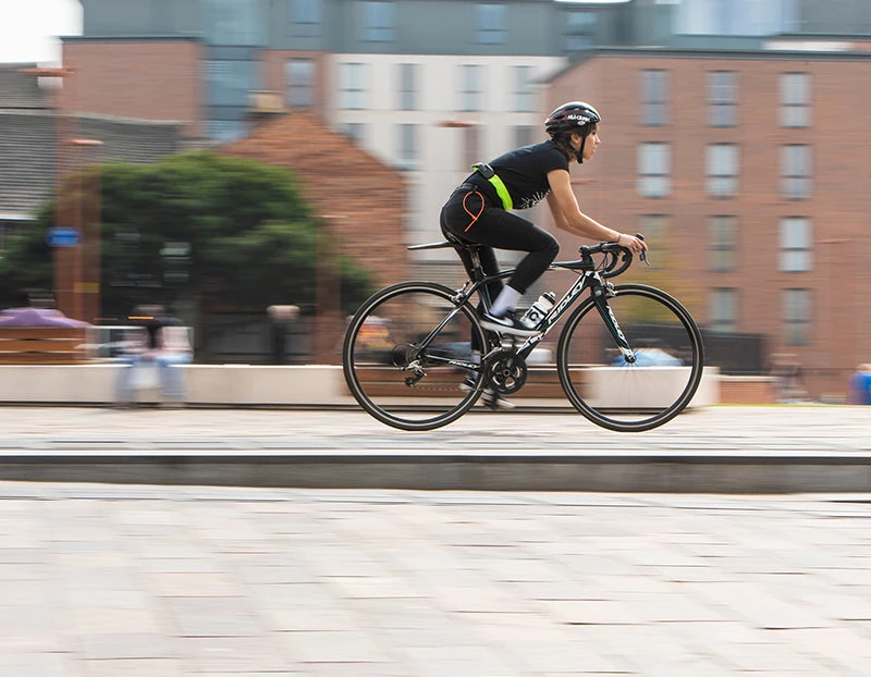 Woman riding through a city with Hiplok SPIN worn round the waist
