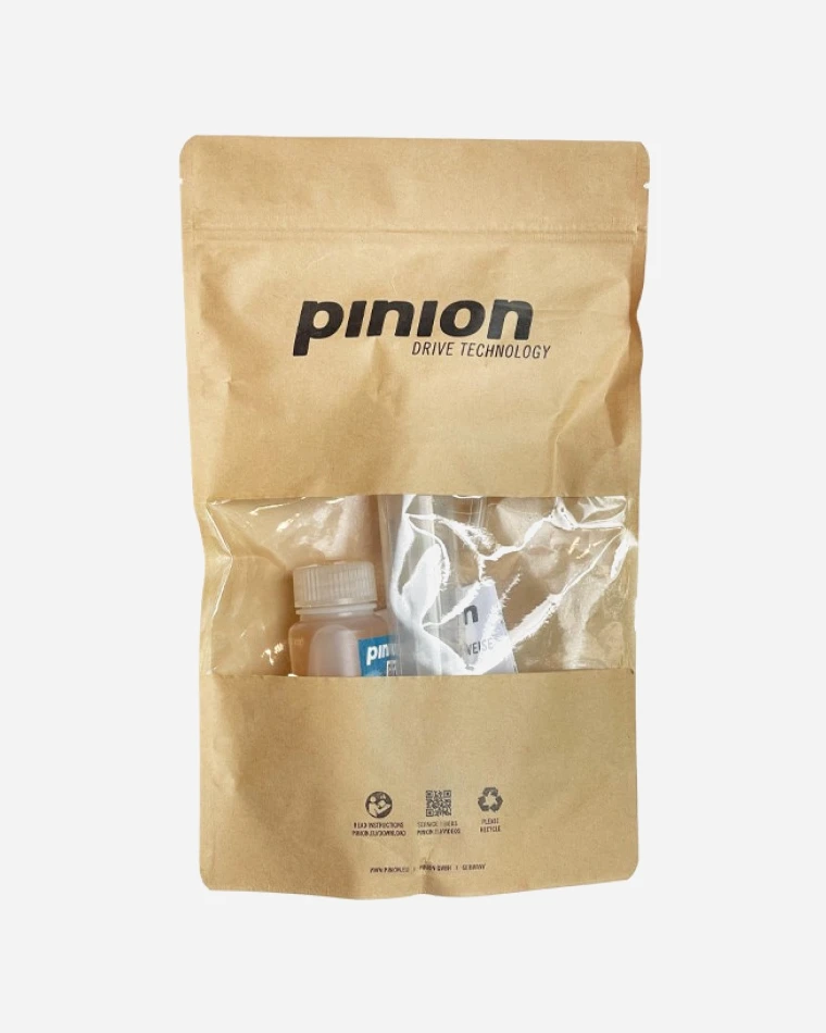 Kraft paper bag of the Pinion oil change kit with the Pinion Drive Technology logo and a window showing the oil bottle