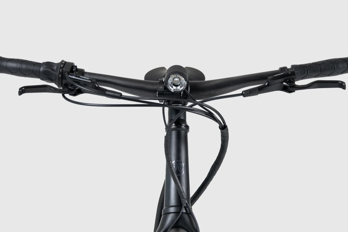 Front view of the Booda Bike Pulse cockpit on a light background: aluminium Noirette handlebar with grips, brake levers and a headlight above the stem