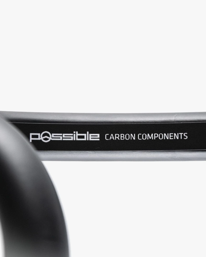 Close-up of the curve of a black Possible carbon road handlebar with the white Possible Carbon Components lettering printed along it