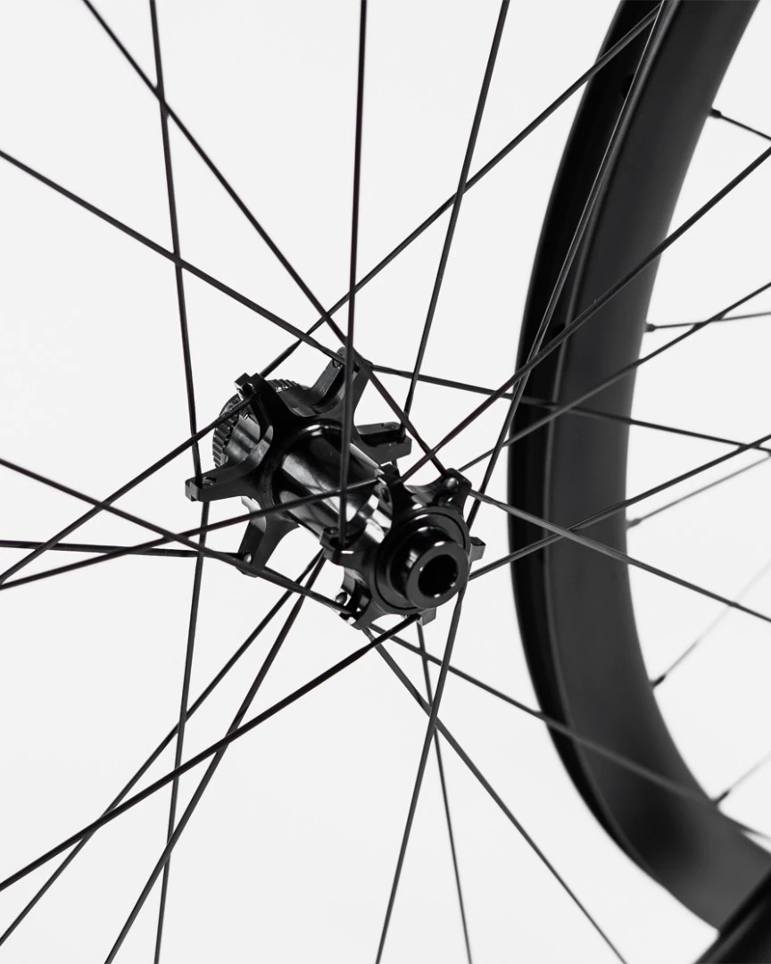 Possible SpinnerOne hub laced with black Sapim Sprint spokes into a carbon rim, close-up