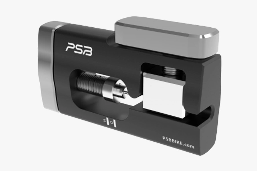 PSB Needle Driver Tool, a black aluminium body with a stainless steel needle holder, a side clamp screw and the PSB logo, seen from the front at an angle