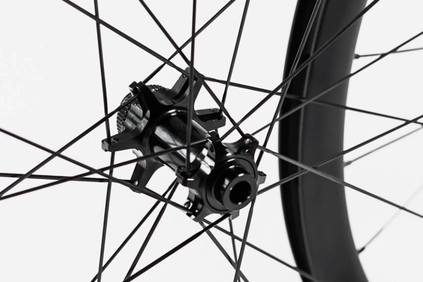 Black straight-pull front hub with black Sapim Sprint spokes running towards a carbon rim