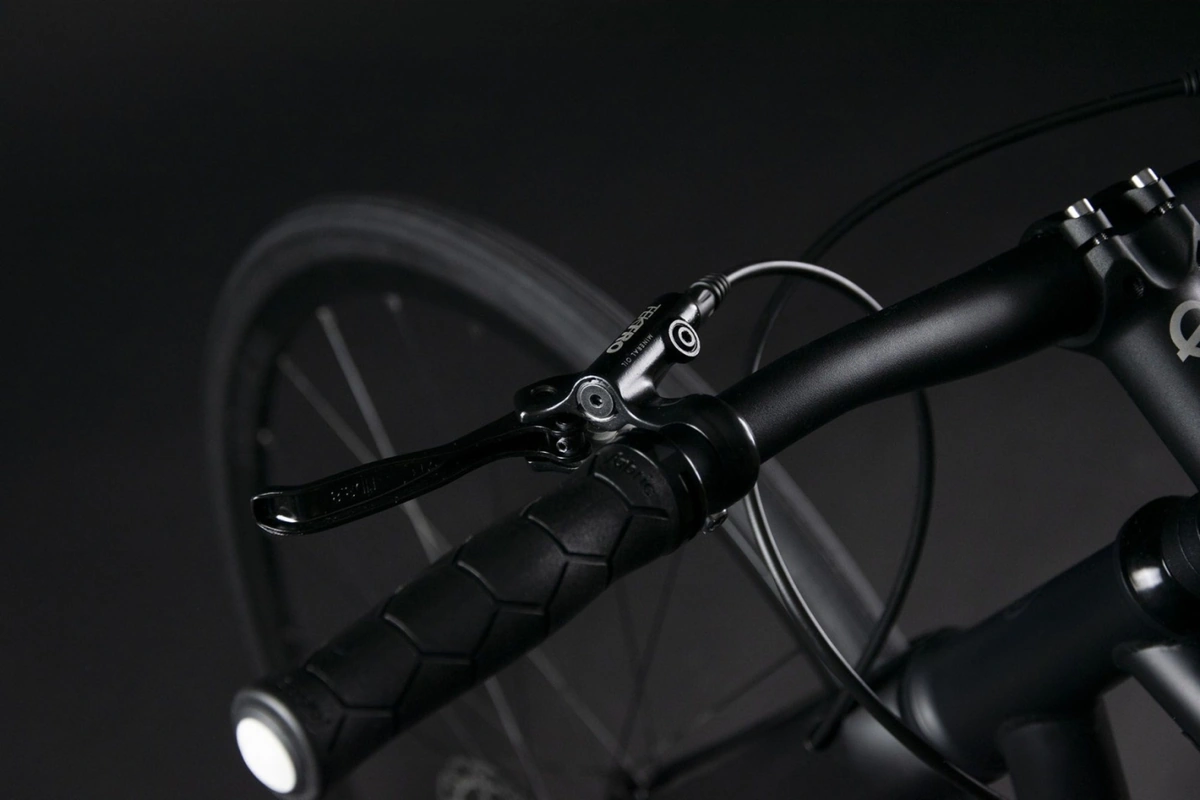 Close-up of the Booda Bike Pilot handlebar with a stem, a ribbed grip and a brake lever, the front wheel blurred behind