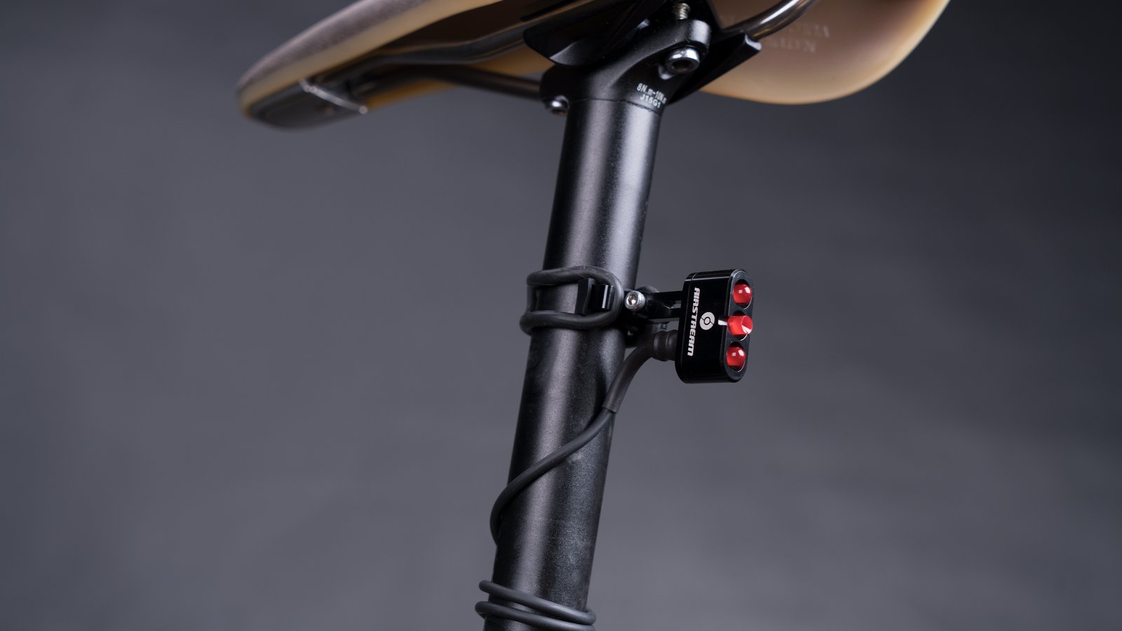 Supernova Airstream Tail Light 2 clamped to a black seat post below the saddle against a dark background