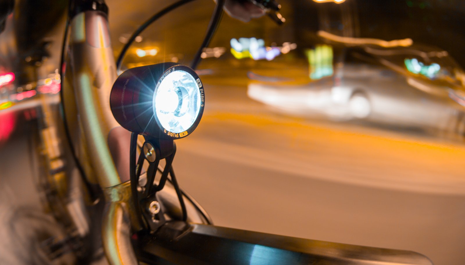 Supernova E3 Pure 3 lit on a city bike at dusk with moving traffic in the background